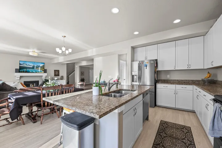 Open-concept kitchen featuring white cabinetry, stainless steel appliances, and a double basin sink