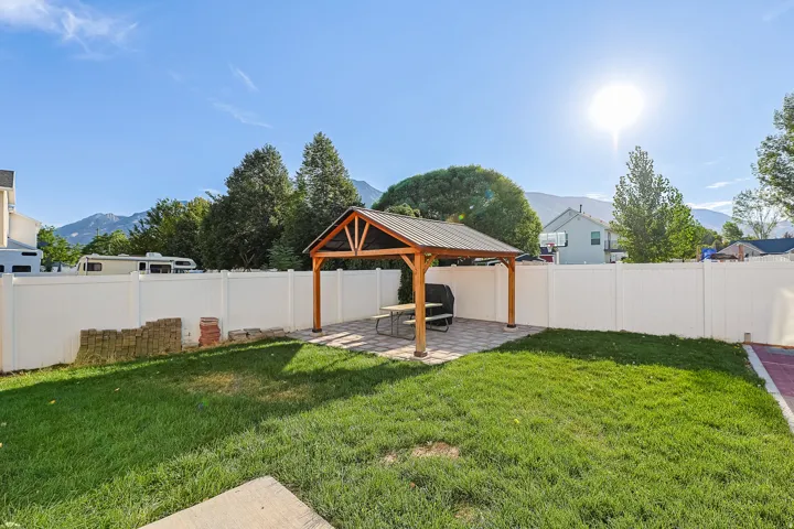 Expansive backyard featuring a central lawn and a white privacy fence