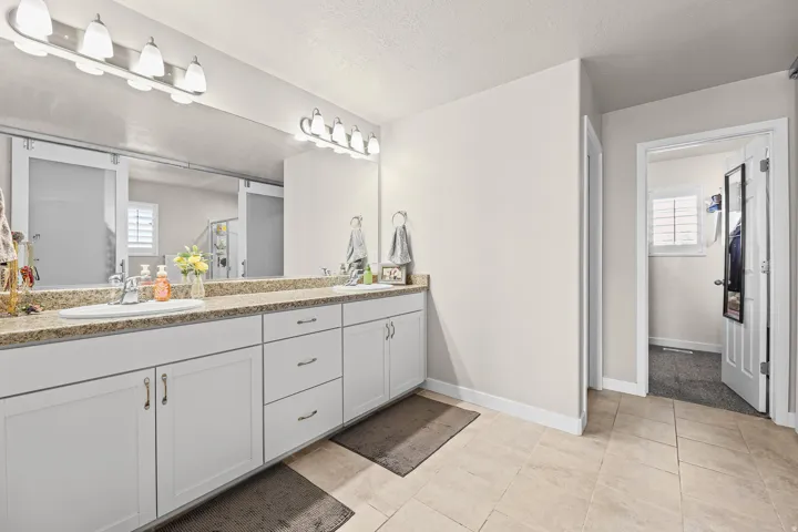 Double vanity with white cabinetry and light-toned countertop, featuring two undermount sinks and individual light fixtures