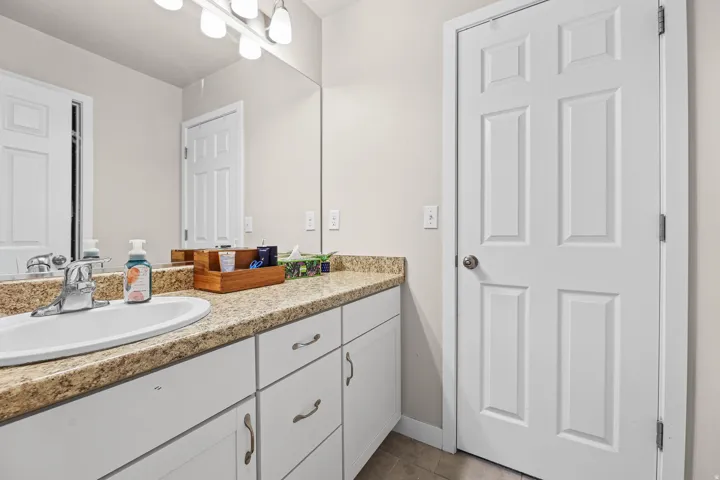 Bathroom vanity featuring an integrated sink, speckled countertop, and white cabinetry with curved hardware