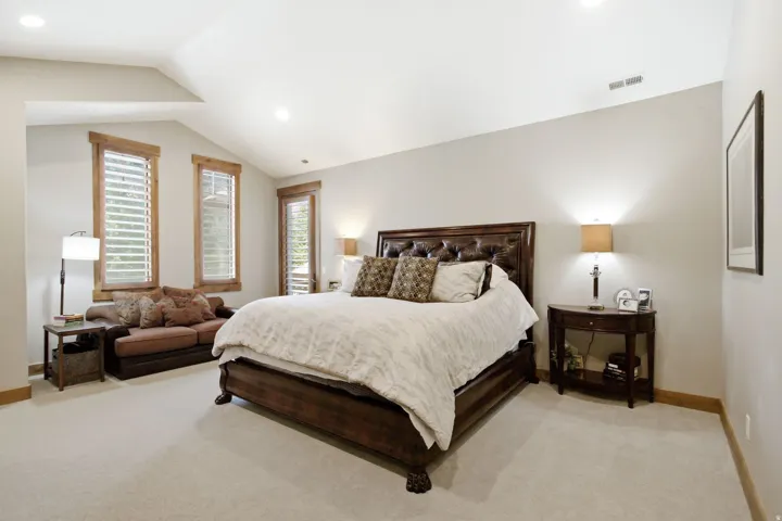 Vaulted ceiling room featuring light-toned walls and plush carpeting