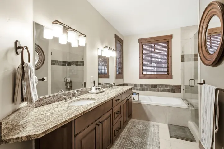 Bathroom featuring a double vanity with granite countertops, wood-finish cabinetry, and undermount sinks
