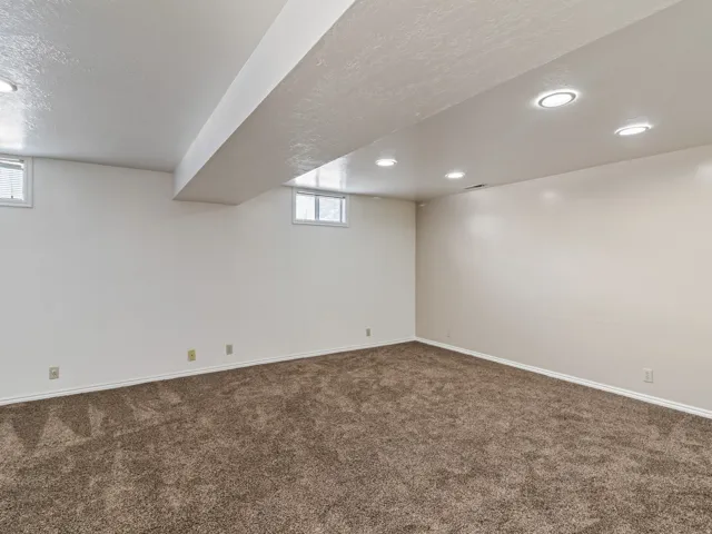 Expansive room featuring recessed lighting, light-toned walls, and plush brown carpeting