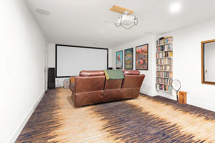 Dedicated media room featuring a large projector screen, ceiling-mounted projector, and integrated ceiling speakers