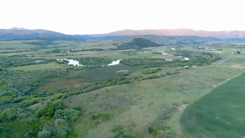 Expansive terrain featuring a winding river, multiple ponds, and distant mountains