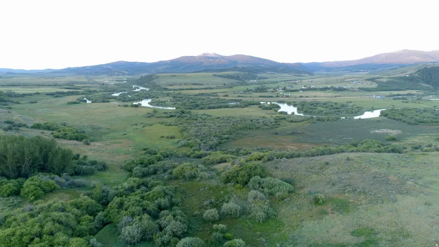 Extensive natural landscape featuring a winding river, dense green brush, and distant mountains
