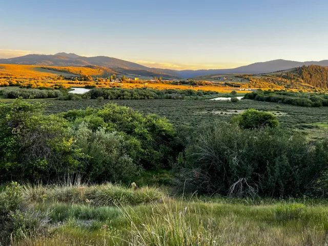 Expansive natural landscape featuring distant mountains, multiple bodies of water, and broad open spaces