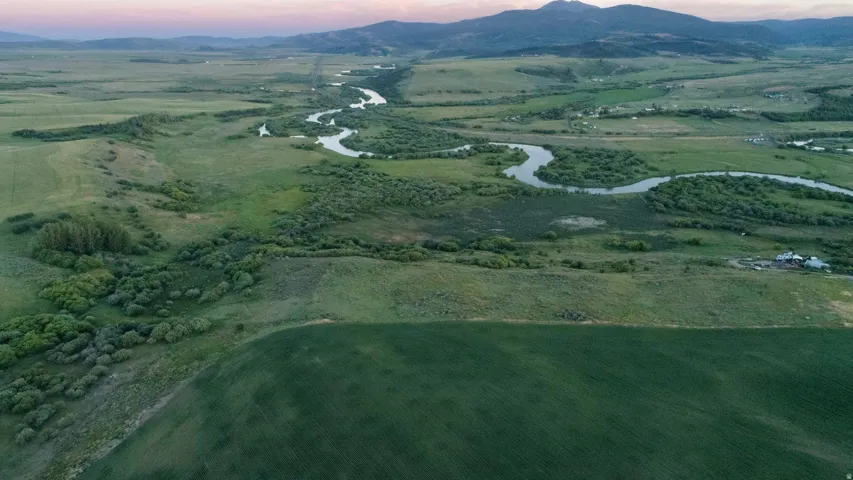 Expansive green landscape featuring a winding river, distant mountains, and cultivated fields