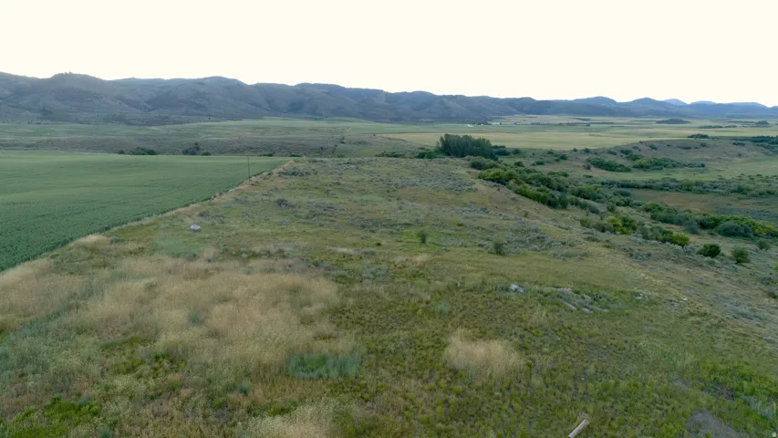 Expansive rural landscape featuring a cultivated field, natural grasslands, and distant hills