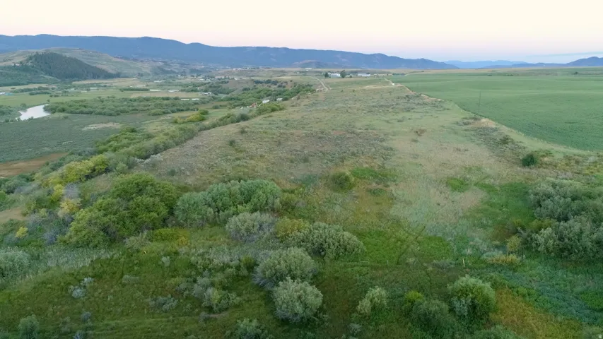 Expansive undeveloped land featuring a meandering river, varied green foliage, and distant mountainous terrain