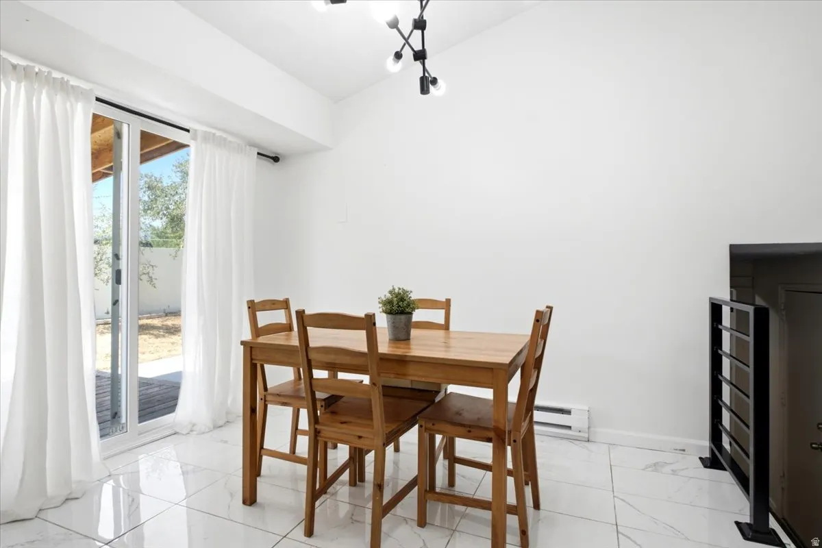 Dining area featuring white walls, glossy white tile flooring, and a modern multi-bulb ceiling fixture