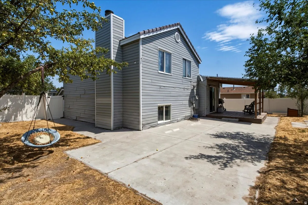 Rear exterior featuring light gray siding, a prominent chimney, and a concrete patio