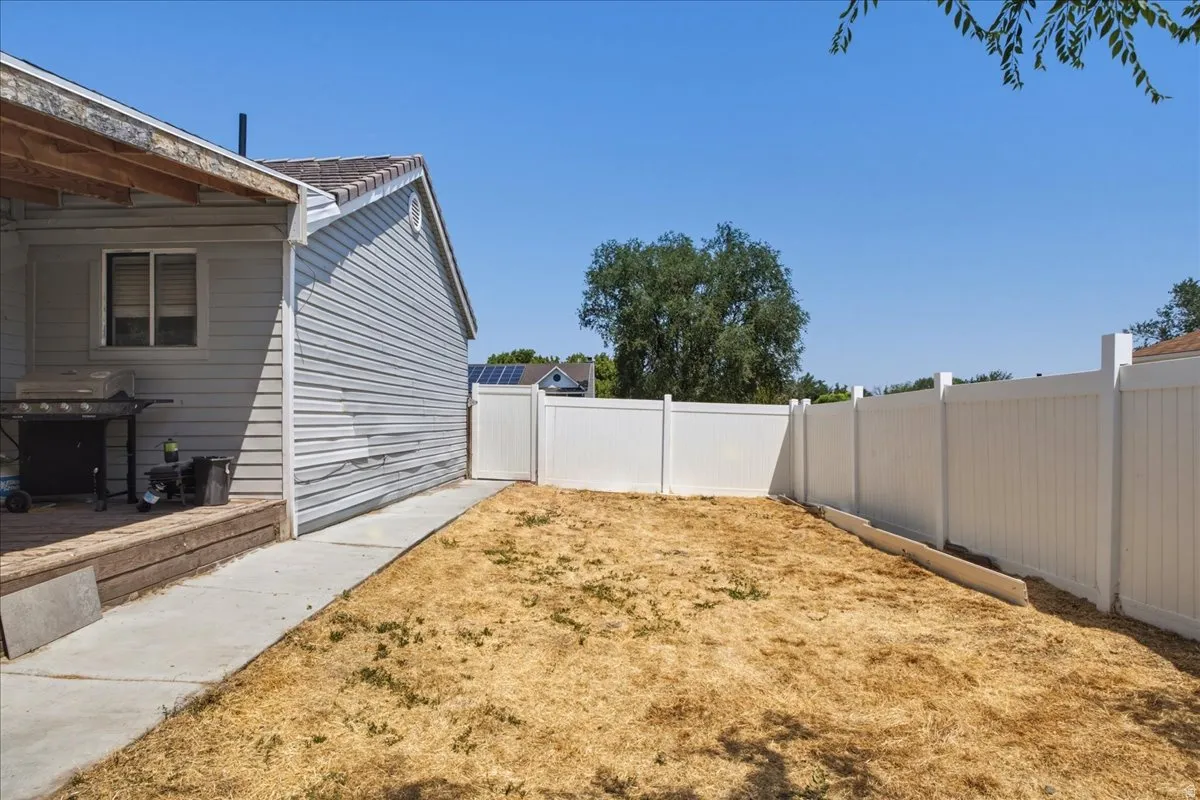Private backyard featuring a full white vinyl fence and a concrete walkway