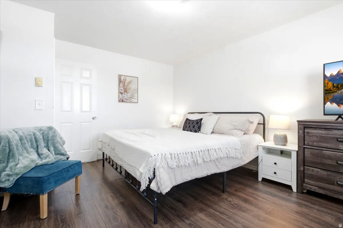 Bedroom featuring wood-finish flooring, white walls, and a white paneled door
