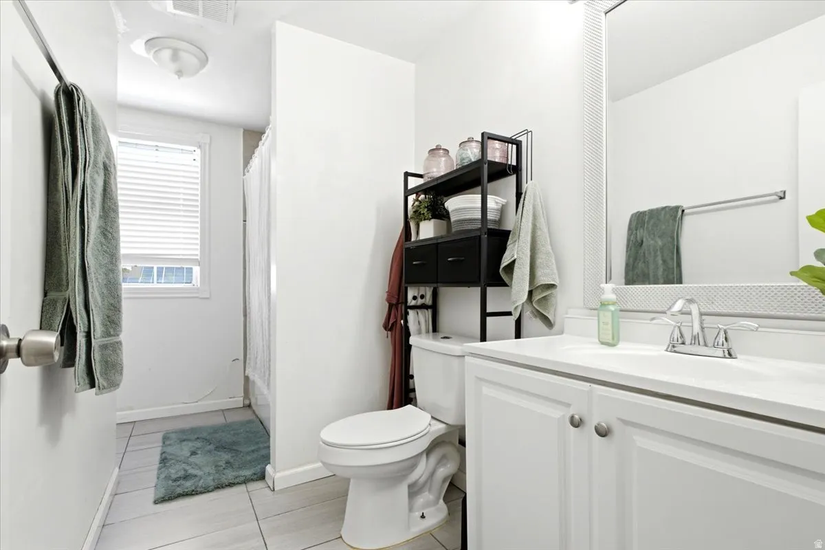 Bathroom featuring a white vanity with integrated sink, chrome faucet, and a large wall mirror