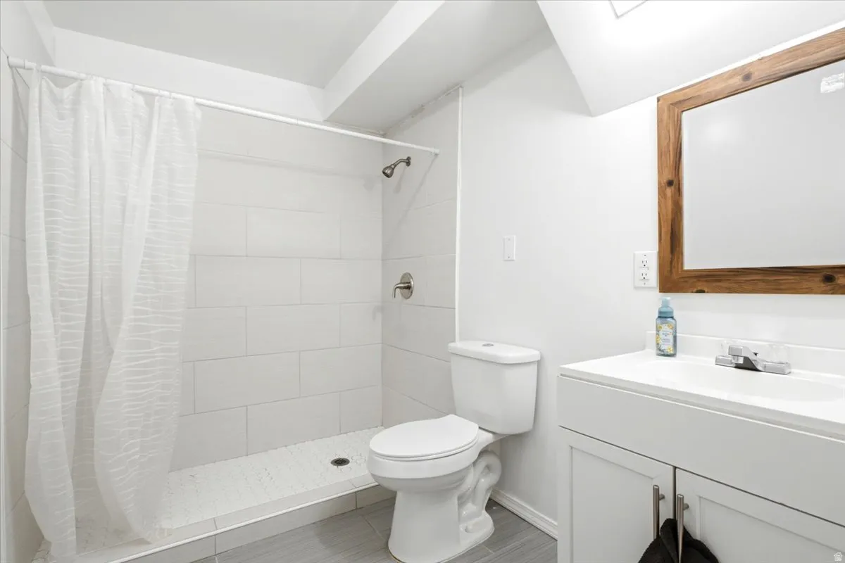 Contemporary bathroom featuring a walk-in shower with white subway tile, a white toilet, and a vanity with a white countertop and base cabinetry