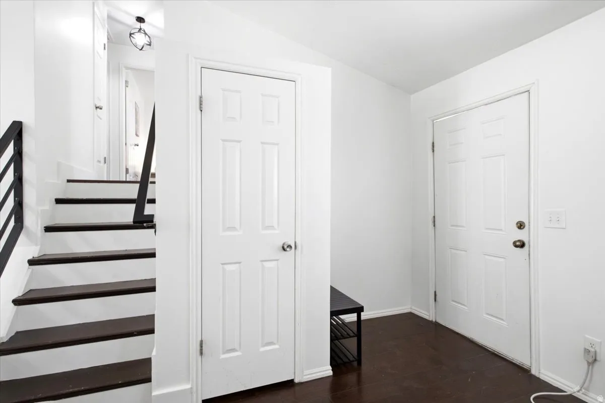 Entryway featuring dark wood-finish flooring, crisp white walls, and a multi-panel door