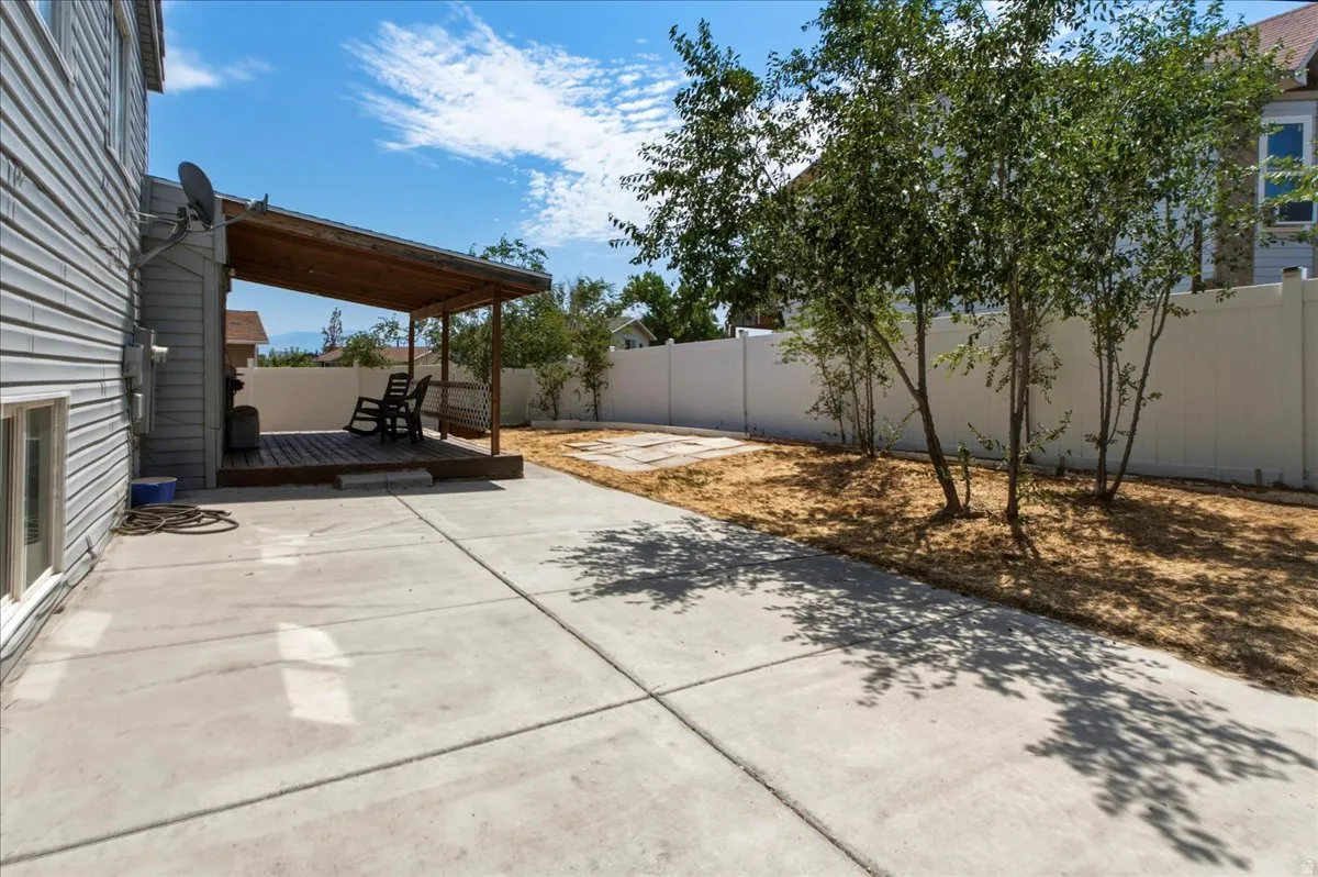 Expansive concrete patio area featuring a covered wooden deck