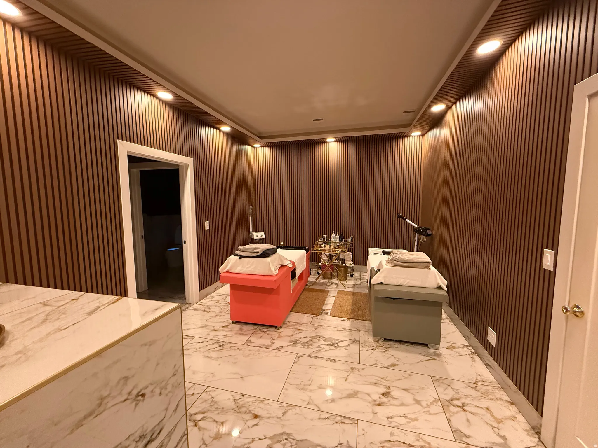 Interior space featuring floor-to-ceiling wood-slat wall paneling, recessed ceiling lighting, and large format marble-look tile flooring
