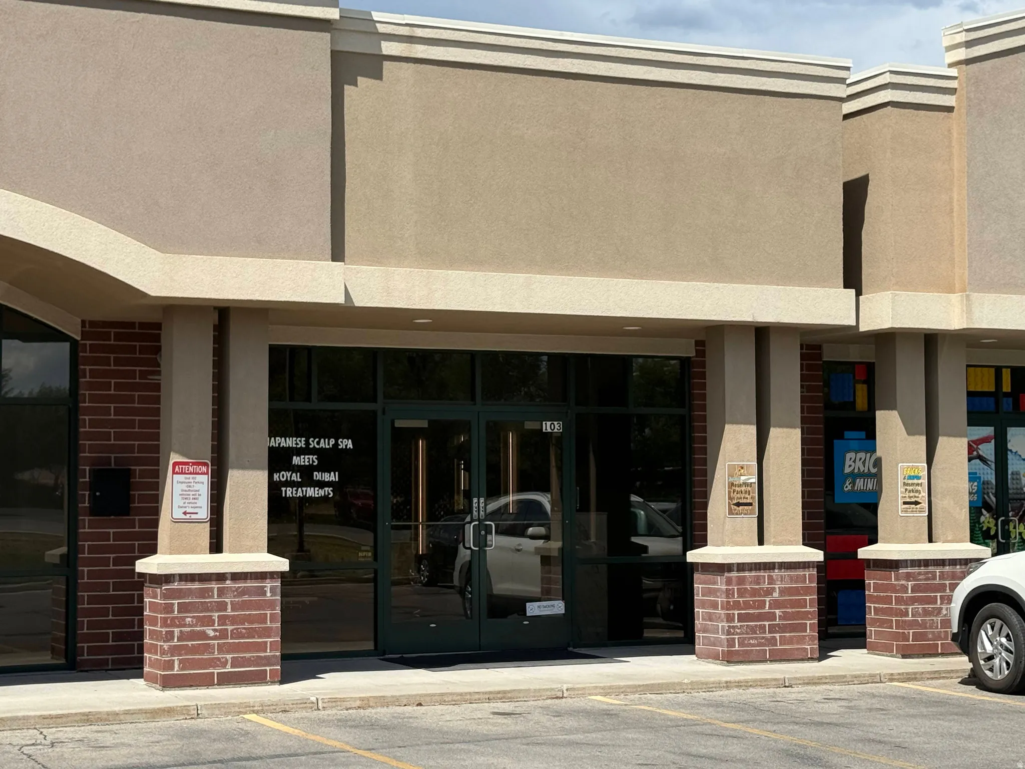 Commercial storefront featuring a glass entry door, large display windows, and brick pilaster bases
