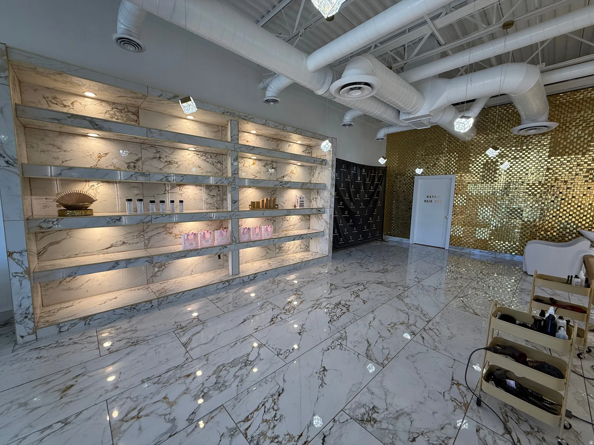 Spacious commercial interior featuring marble-finish tile flooring and an integrated wall display unit with recessed lighting