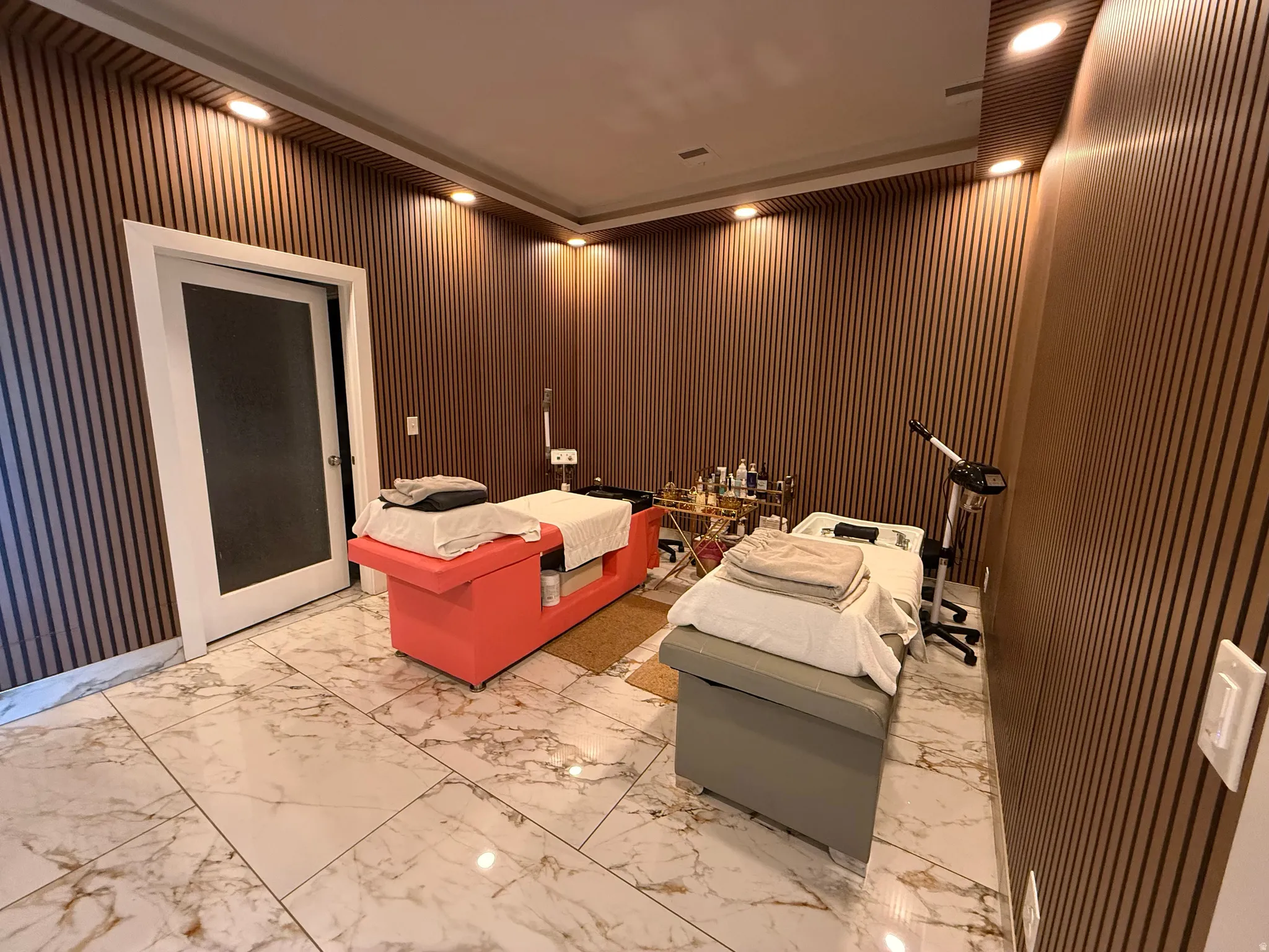 Room featuring wood-slat wall paneling, recessed ceiling lighting, and large format marble-look tile flooring