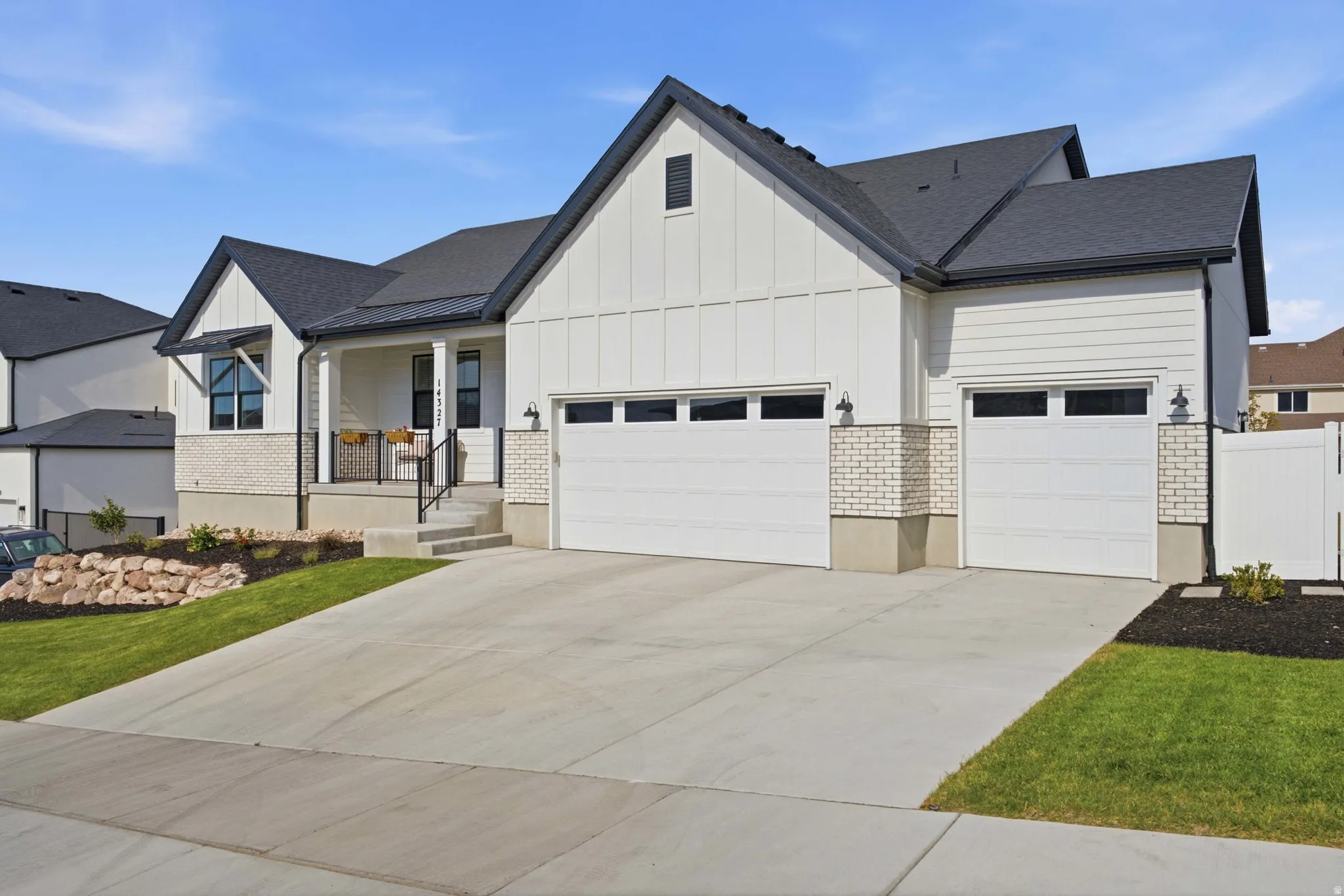 Contemporary farmhouse exterior featuring white board-and-batten siding with coordinating horizontal siding, a dark shingle roof, and light brick accents
