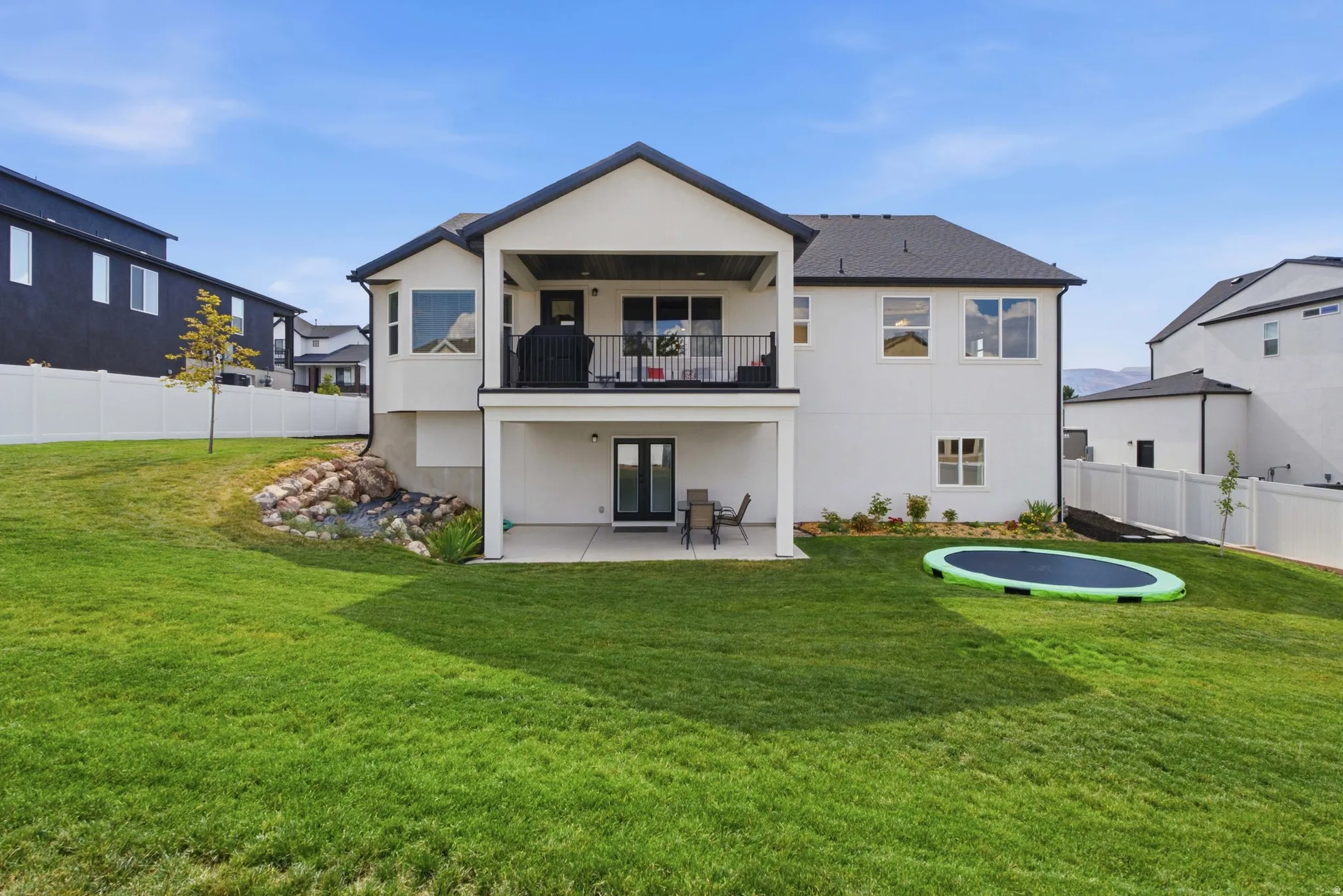 Rear exterior featuring a covered upper-level balcony, a lower-level patio, and an expansive lawn, ADU Entrance