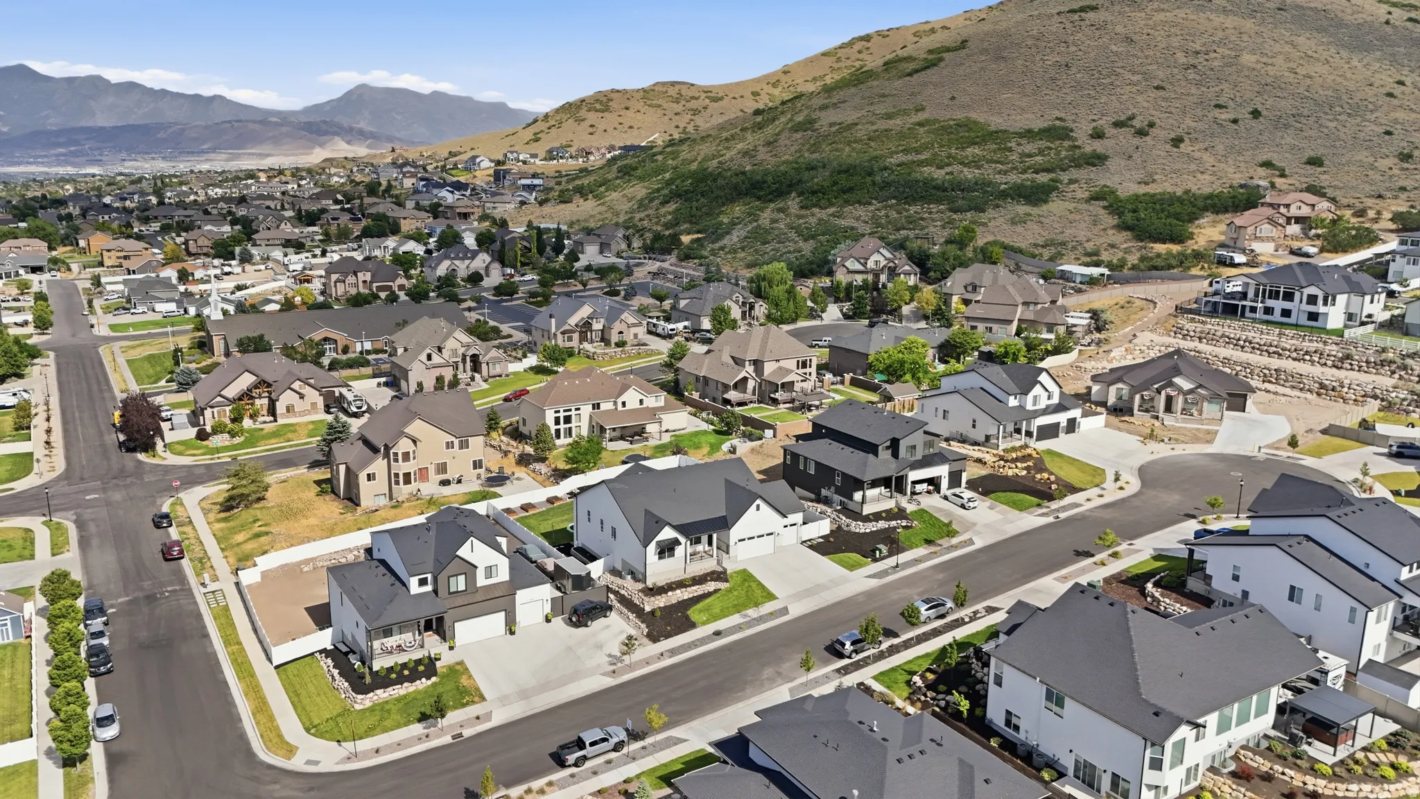 Expansive residential community featuring a variety of architectural styles, paved streets, and mountainous surroundings