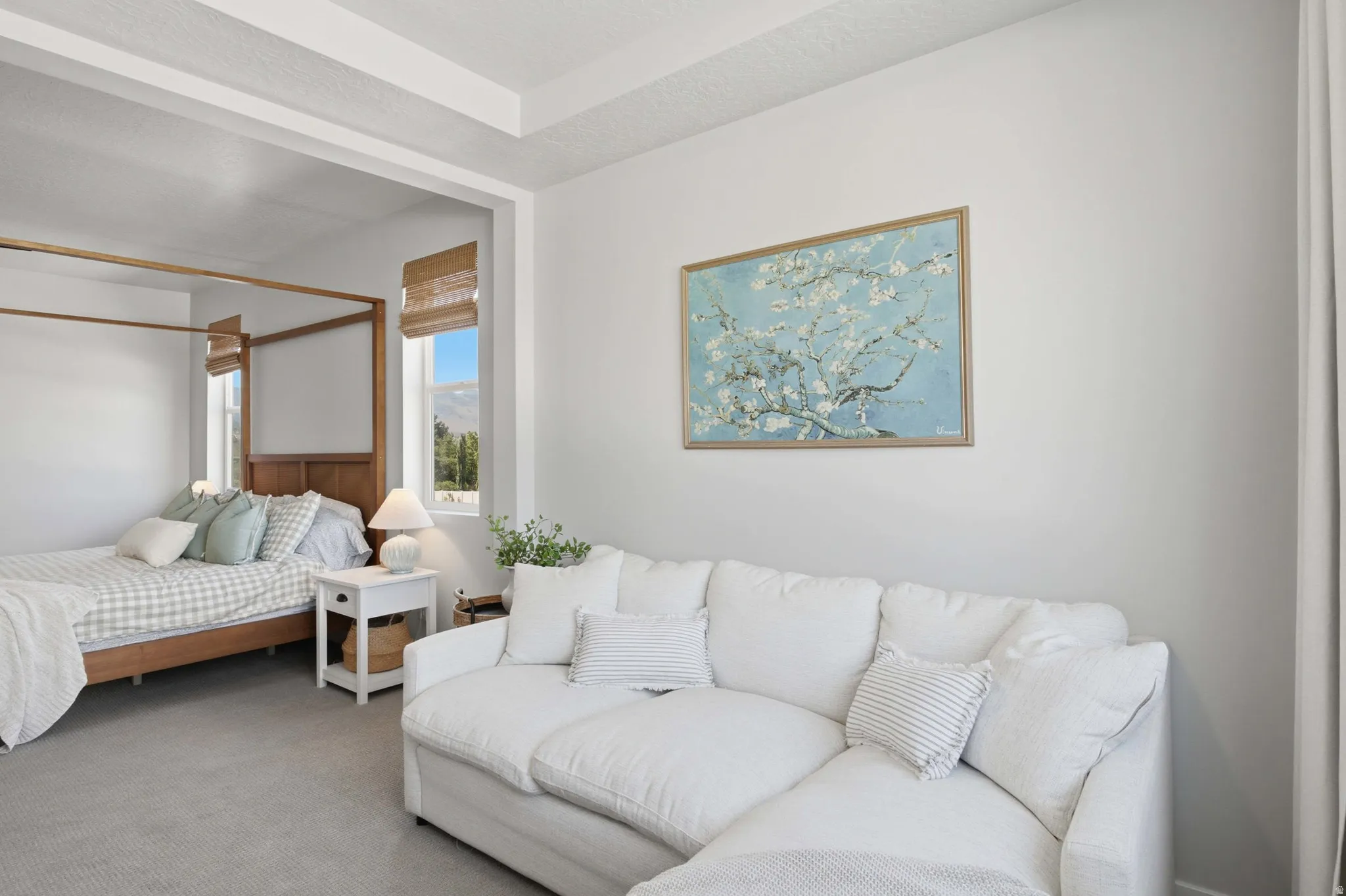 Primary Bedroom featuring a white upholstered sectional, tray ceiling, and a distinct alcove with two windows