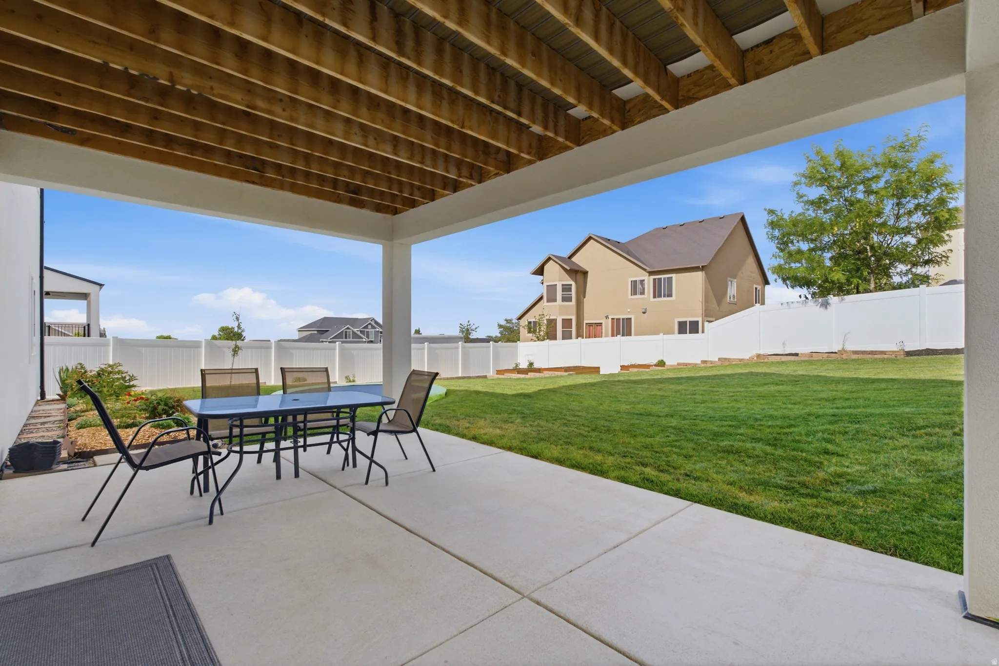 Covered patio with concrete flooring, featuring a wood-finish ceiling and white support columns