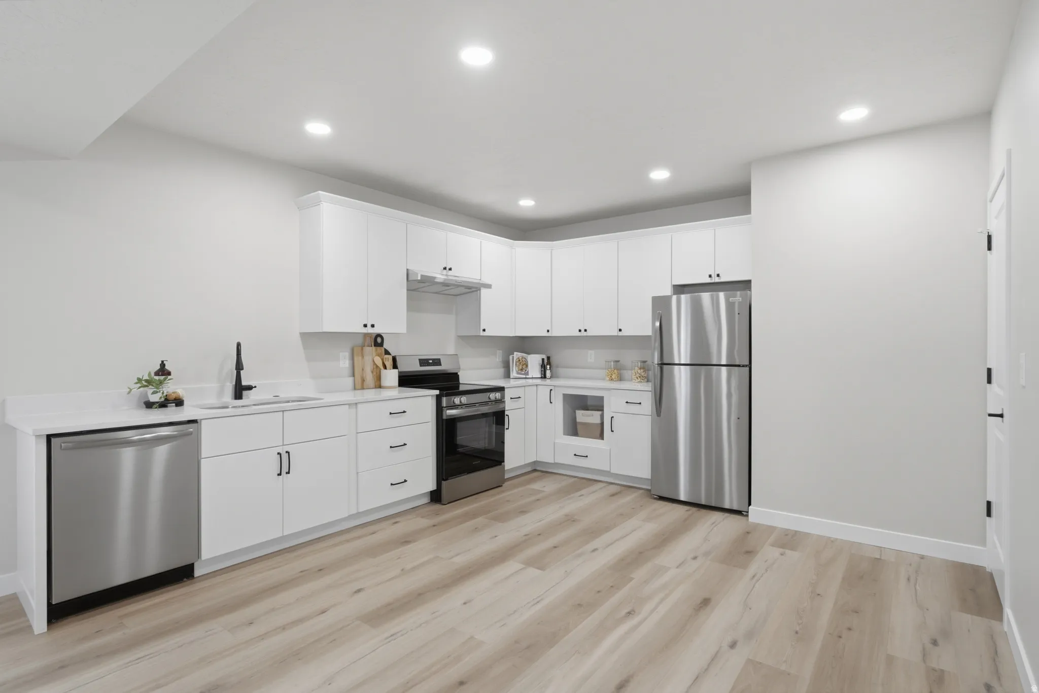 Contemporary kitchen with white cabinetry, new stainless steel appliances.