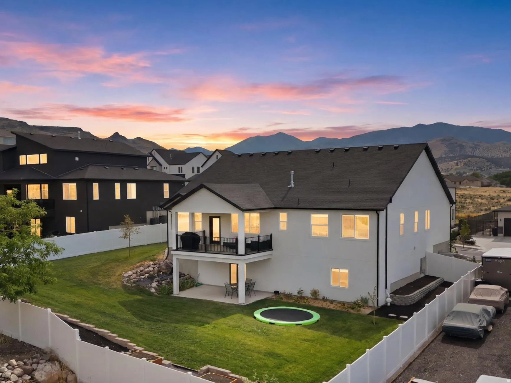 White two-story residence featuring a dark roof and a rear balcony