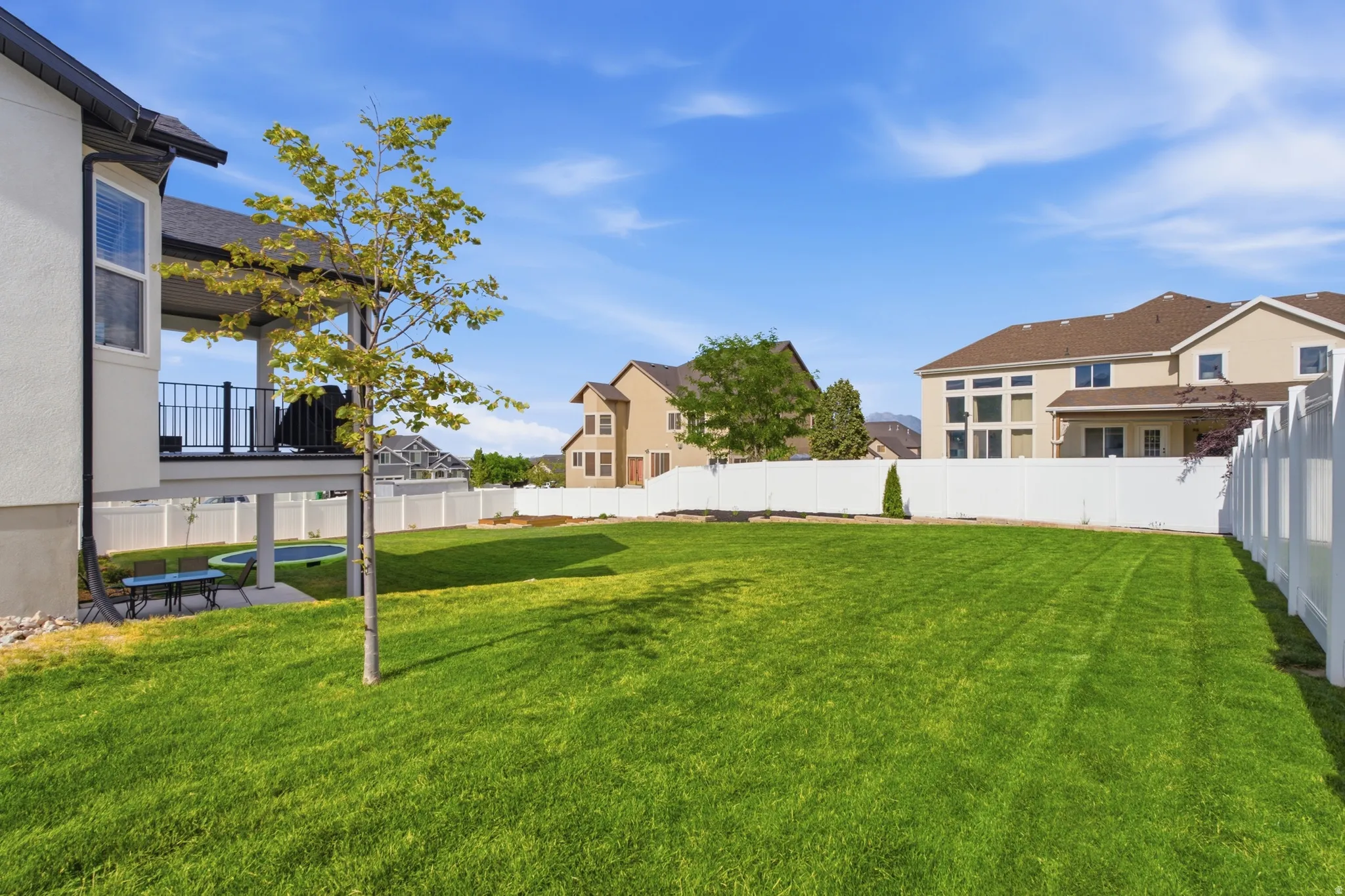 Expansive green lawn framed by a white privacy fence