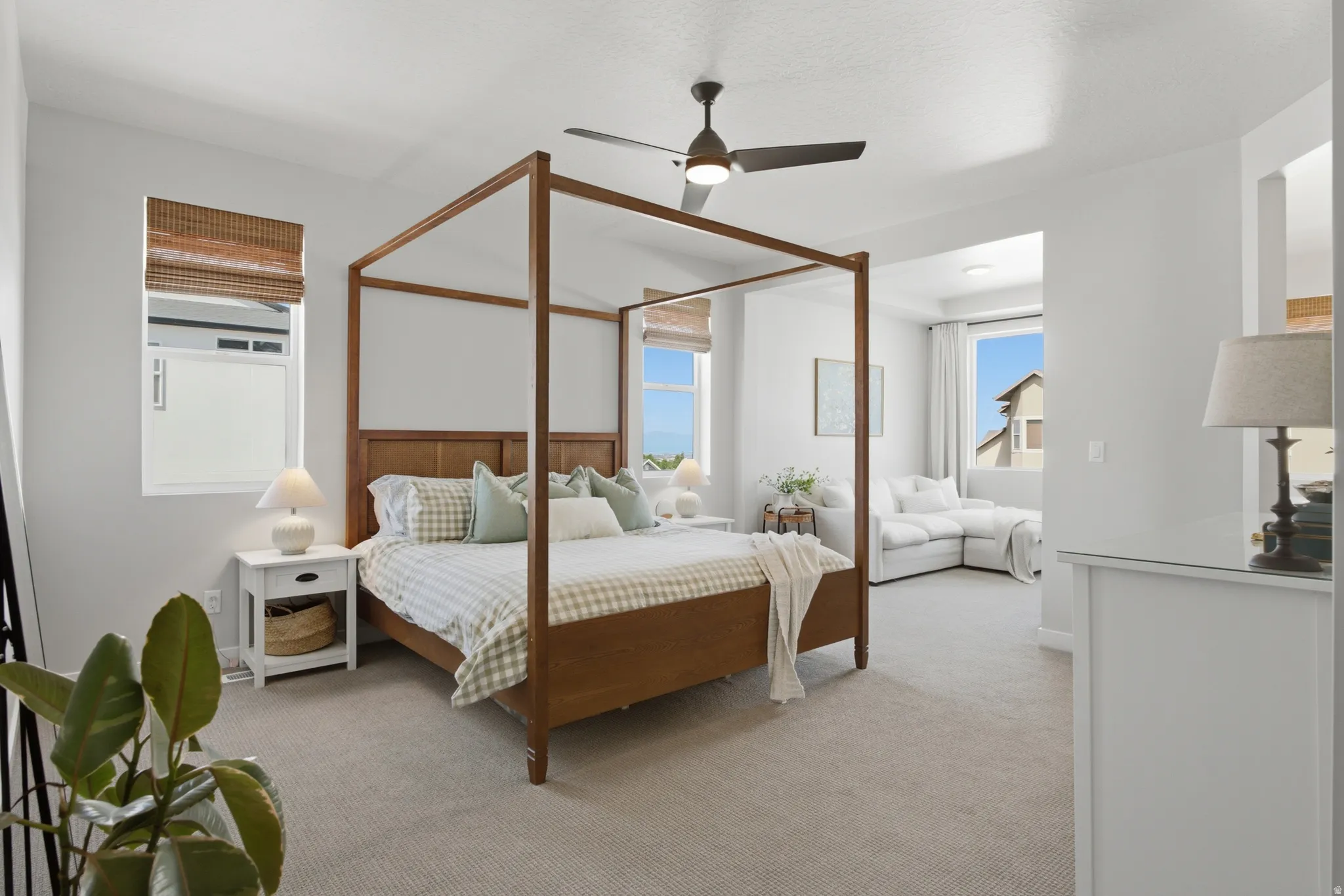 Expansive bedroom featuring light gray carpeting, a ceiling fan, and multiple windows with natural light