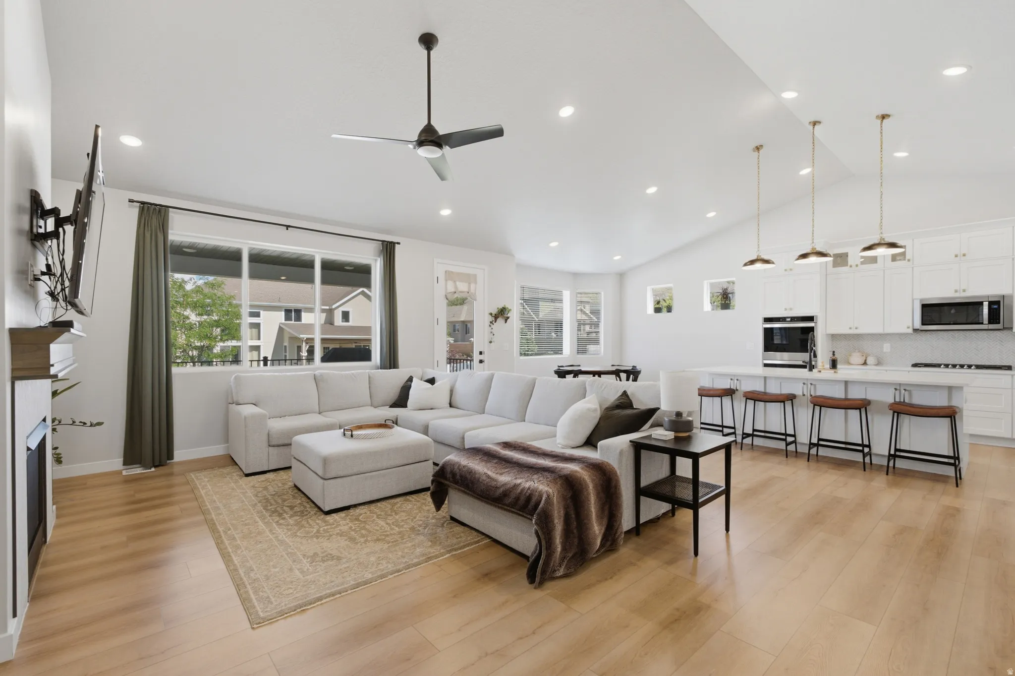 Open-concept living area featuring a vaulted ceiling and wood-finish flooring