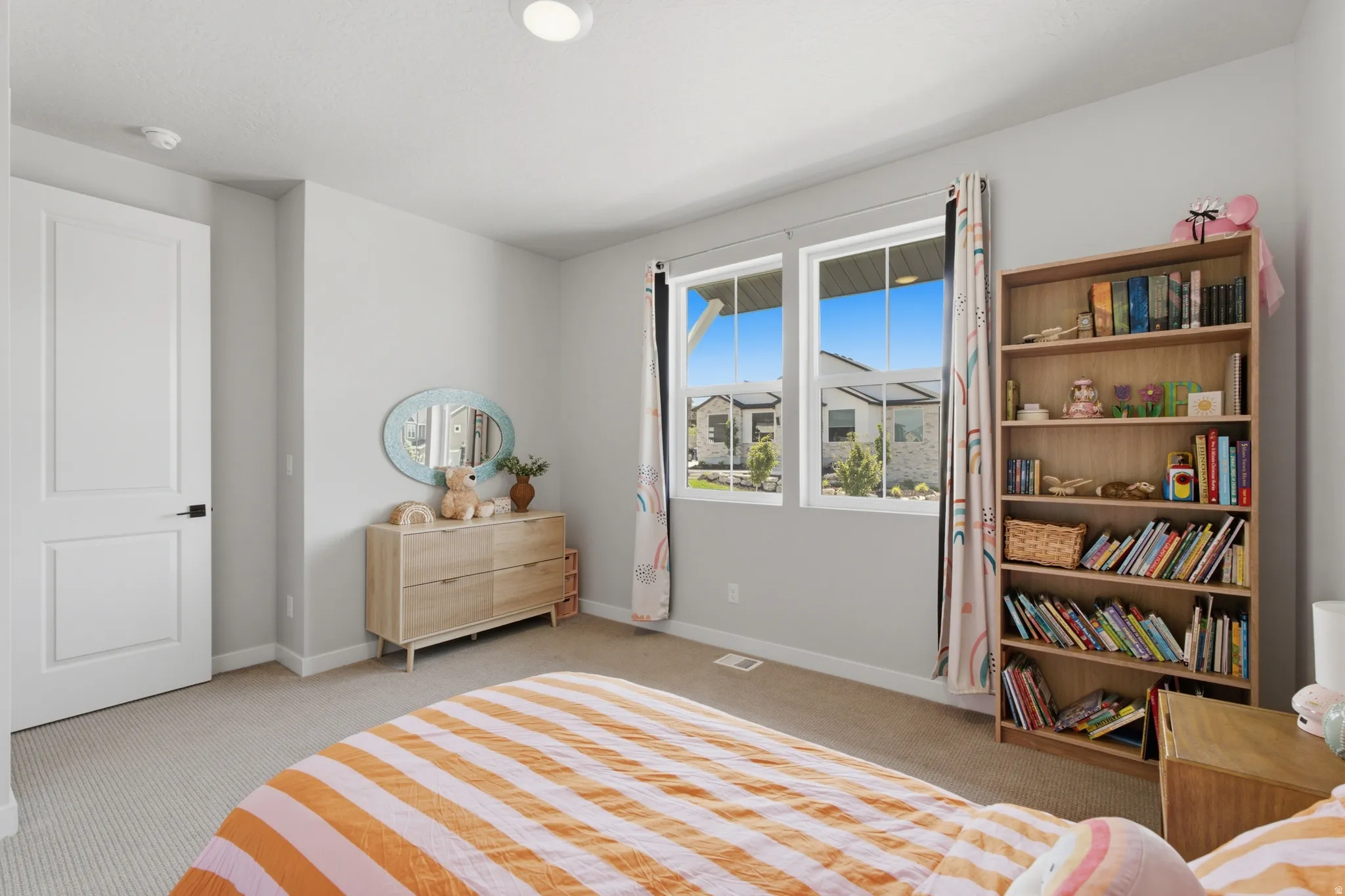 Bedroom Two with dual pane windows providing natural light, recessed ceiling lighting, textured carpet flooring, painted interior door with dark hardware, and light-toned walls
