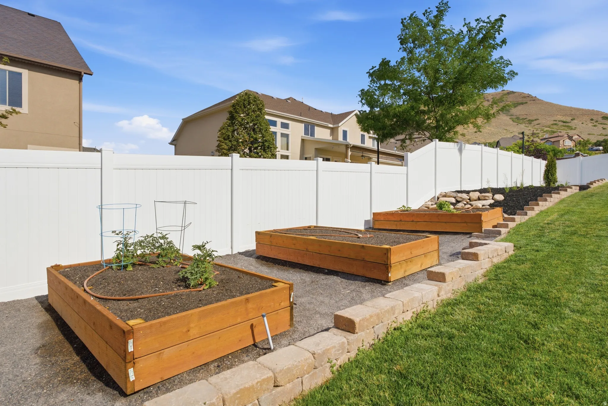 Tiered backyard landscaping featuring three raised garden beds with irrigation