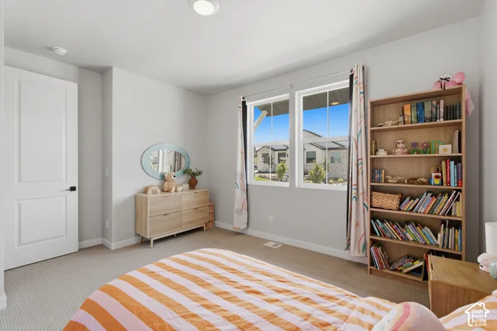 Bedroom Two with dual pane windows providing natural light, recessed ceiling lighting, textured carpet flooring, painted interior door with dark hardware, and light-toned walls