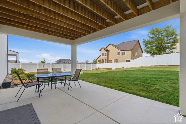 Covered patio with concrete flooring, featuring a wood-finish ceiling and white support columns