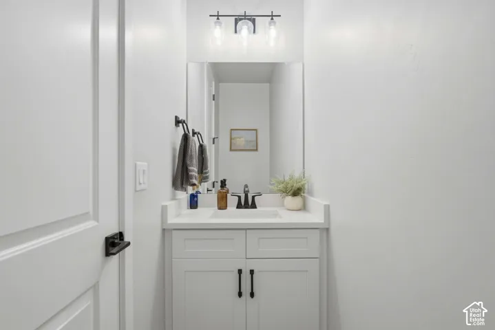 Guest Bathroom with white vanity with shaker-style cabinetry, a built-in sink, and a white countertop