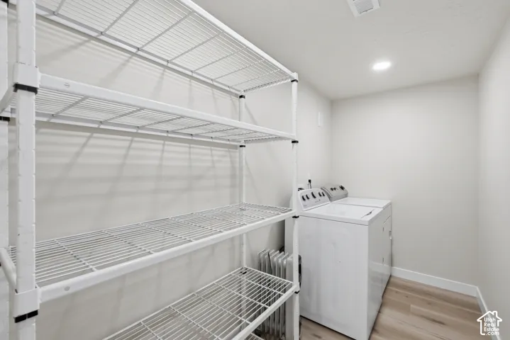 ADU Utility area featuring extensive wire shelving, light wood-finish flooring, recessed lighting, and a white baseboard trim
