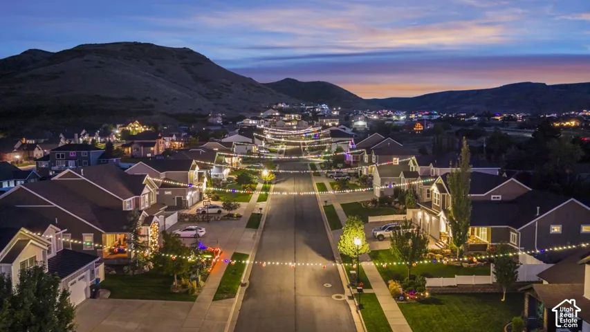 Residential street with single-family homes, illuminated streetlights, and distant mountain scenery