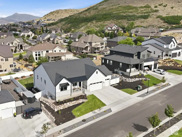 Modern farmhouse-style residence with a dark gray roof and white siding, featuring a two-car garage and a landscaped front yard with decorative rock walls