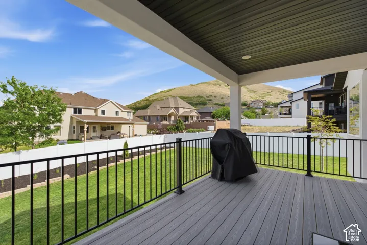 Covered outdoor deck with composite decking, black metal railings, and a slatted ceiling with recessed lighting