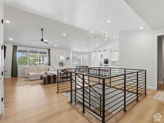 Open-concept living area with wood-finish flooring, recessed lighting, and a contemporary black metal balustrade