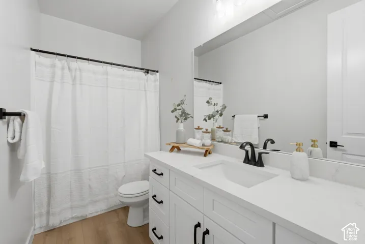 Full Bathroom featuring a large single vanity with a white quartz countertop and integrated sink, matte black faucet, and white shaker-style cabinetry with black hardware