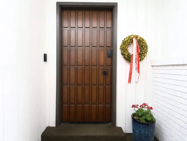 Rich wood-finish entry door with panel detailing and dark trim