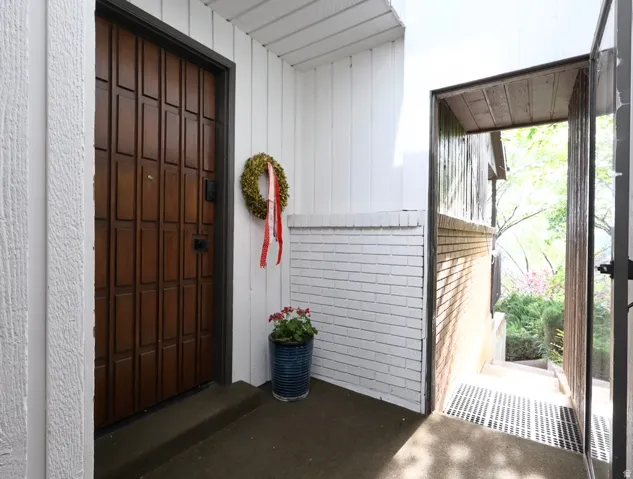 Panel-style front entry door with a dark frame, complemented by white vertical siding and a painted brick accent wall