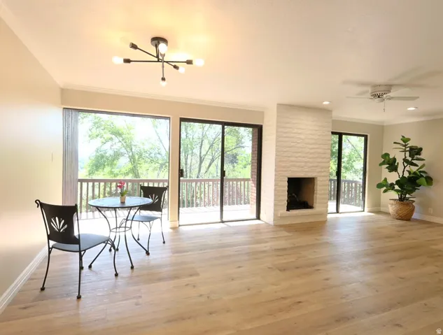 Spacious interior featuring wide plank wood-finish flooring, a white brick fireplace, and two sets of sliding glass doors opening to a wood deck